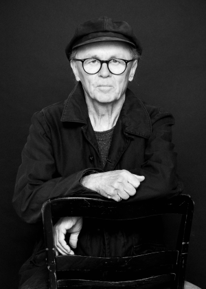 Der Fotograf Franz Bauer, eine schwarze Kamera in der Hand haltend